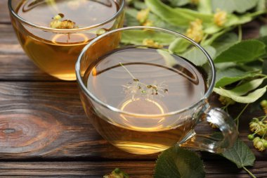 Fincanlarda taze ıhlamur çayı ve ahşap masada çiçekler, yakın plan.