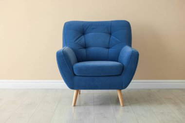 Bej duvarın yanındaki rahat, yumuşak, mavi koltuk.