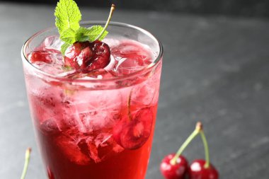 Buzlu vişneli gazoz, böğürtlen ve nane şekeri gri masada, yakın plan. Metin için boşluk