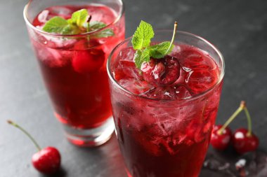 Buzlu vişneli gazoz, böğürtlen ve nane şekeri. Gri masada, yakın plan.