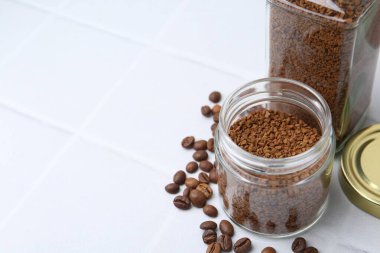 Kavanozlarda hazır kahve, beyaz fayanslı masa, yakın plan. Metin için boşluk