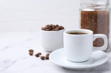 Aromatik sıcak içecek, hazır kahve ve fasulye beyaz mermer masada, yakın plan. Metin için boşluk