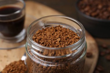 Cam kavanozdaki anlık kahve, masada sıcak içecek ve fasulye, yakın plan.