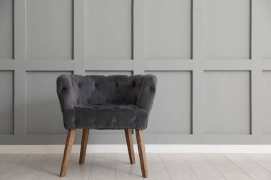 Açık gri duvarın yanındaki rahat koltuk. Kapalı alan, metin için yer.