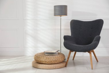 Rahat gri koltuk, lamba ve beyaz duvarın yanında kitaplar, metin için yer