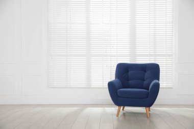 Beyaz duvarın yanındaki rahat mavi koltuk, metin için boşluk.