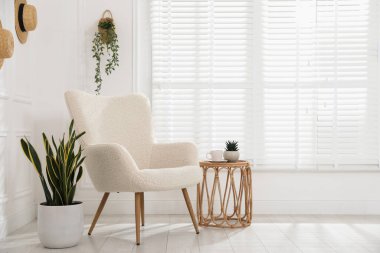 Rahat koltuk, yan masa ve beyaz duvarın yanındaki ev bitkileri, metin için yer