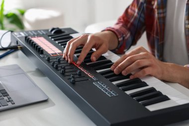 Beyaz masada MIDI klavyesiyle çalışan adam, yakın plan.