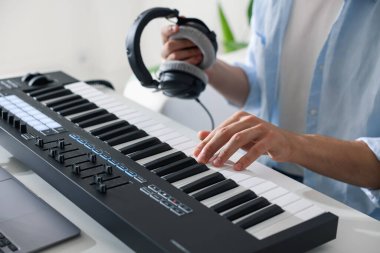 İçerideki masada MIDI klavyesiyle çalışan adam, yakın plan.