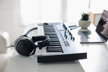 MIDI klavye, kulaklık ve dizüstü bilgisayar kapalı beyaz ahşap masa, yakın plan