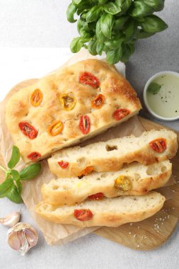 Domatesli, baharatlı ve yağlı nefis Focaccia 'yı gri masaya koyun.