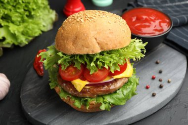 Köfteli lezzetli hamburger, siyah masada servis ediliyor, yakın plan.