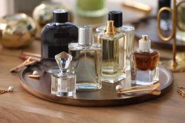 Farklı parfüm şişeleri ve aksesuarlar ahşap masada, yakın plan.