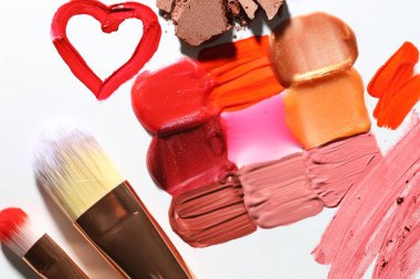 Beyaz arka planda farklı kozmetik ürünler ve makyaj fırçaları, düz yatış