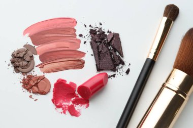 Beyaz arka planda farklı kozmetik ürünler ve makyaj fırçaları, düz yatış