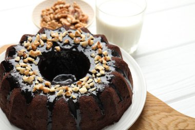 Fındıklı çikolatalı kek ve beyaz ahşap masada bir bardak süt, yakın plan.