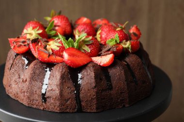 Çilekli, naneli ve çikolatalı kek bulanık arka planda duruyor, yakın planda.