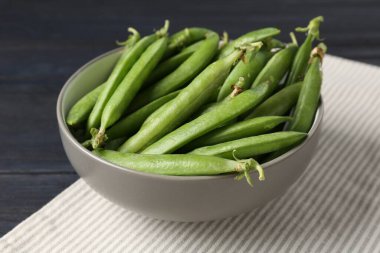 Taze taze bezelyeler siyah ahşap masada, yakın plan.