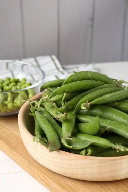 Taze taze bezelyeler beyaz ahşap masada, yakın plan.