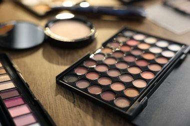 Ahşap masada farklı makyaj ürünleri, yakın plan.