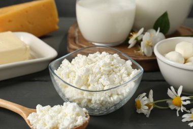 Gri ahşap masada taze süt ürünleri ve çiçekler, yakın plan.