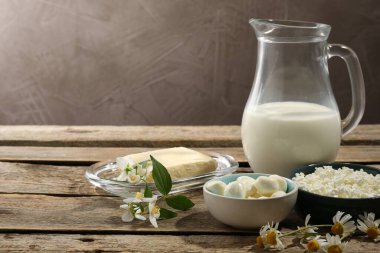 Farklı taze süt ürünleri ve çiçekler ahşap masa üzerinde, metin için yer