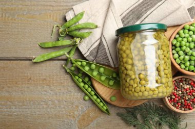 Kavanozda bezelye turşusu, baharatlar, ahşap masa üzerinde dereotlar ve kabuklar. Metin için boşluk