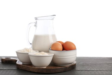 Gri ahşap masada beyaz arka planda farklı süt ürünleri ve yumurtalar