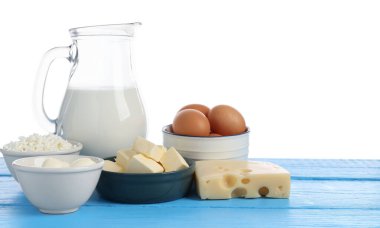 Farklı süt ürünleri ve yumurtalar mavi ahşap masada beyaz arka planda