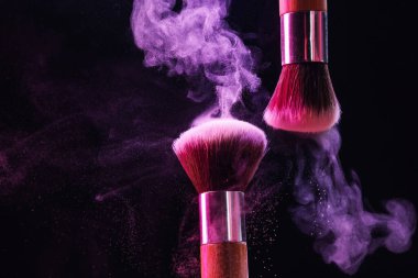 Renkli göz gölgeli makyaj fırçaları siyah arka planda neon ışıkları, yakın plan