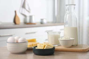 Mutfaktaki ahşap masada farklı süt ürünleri ve yumurtalar.