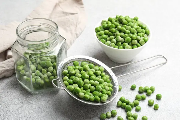 Açık gri masada taze bezelye ve turşu kavanozu, yakın plan.