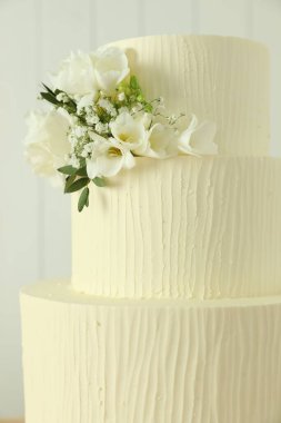 Bulanık arkaplanda çiçek dekoru olan lezzetli düğün pastası, yakın plan.