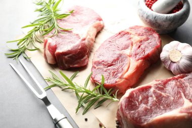 Çiğ et, baharat ve çatal parçaları gri masada, yakın plan.