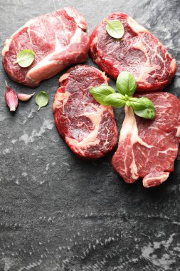 Koyu masa üzerinde çiğ et ve fesleğen parçaları. Metin için boşluk