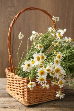 Güzel papatya çiçekleri hasır sepetin içinde ahşap masanın üzerinde, yakın plan
