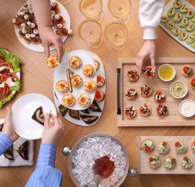 Açık büfe menüsü. İnsanlar ahşap masadan lezzetli aperatifler alıyor.