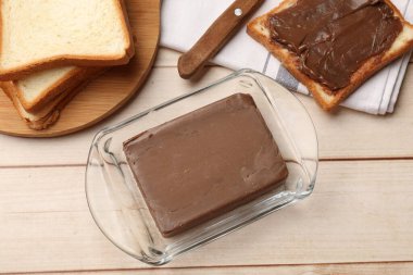 Lezzetli bir kalıp çikolatalı tereyağı kalecide ve ekmek dilimleri açık ahşap masada, düz uzanıyordu.