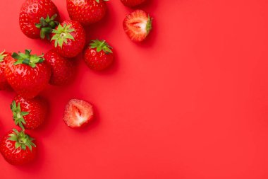 Kırmızı arka planda taze olgun çilekler, düz uzanmış. Metin için boşluk