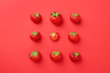 Kırmızı arka planda taze olgun çilekler, düz uzanmış.