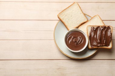 Çikolatalı tereyağı ve ekmek dilimleri açık ahşap masa, üst manzara. Metin için boşluk