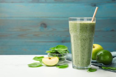 Lezzetli ıspanaklı smoothie ve beyaz mermer masada malzemeler, yakın plan. Metin için boşluk
