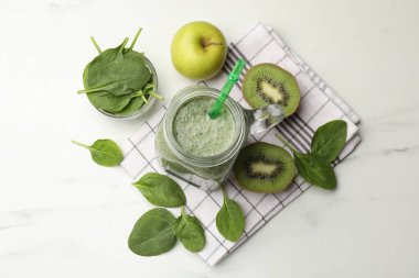 Mason kavanozunda leziz bir smoothie, ıspanak yaprakları, kivi ve elma beyaz mermer masada, düz yatıyordu.