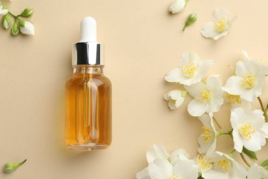 Temel yağ ve güzel yasemin çiçekleri bej arka planda, düz yatıyordu.