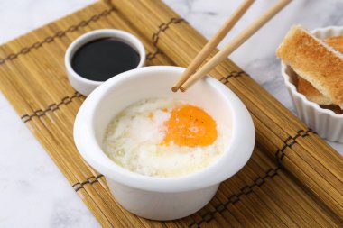 Kavanozda yarı haşlanmış yumurta, soya sosu, yemek çubukları ve beyaz mermer masada kızarmış ekmek, yakın plan. Geleneksel Asya kahvaltısı