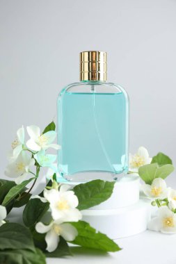 Bir şişe parfüm ve arka planda yasemin çiçekleri, yakın plan.