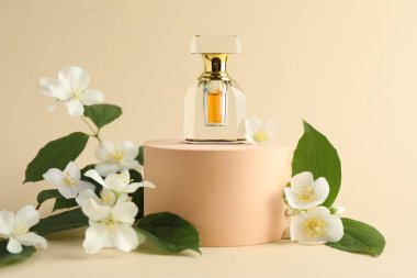 Bir şişe parfüm ve bej arka planda yasemin çiçekleri.