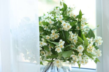 Güzel yasemin çiçekleri pencerenin yanındaki vazoda, yakın plan.