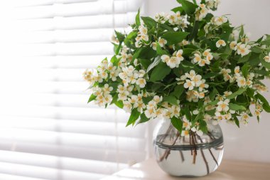 Güzel yasemin çiçekleri vazonun içinde pencerenin yanındaki masada, yakın plan. Metin için boşluk