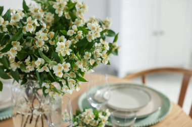 İçerideki yemek masasının üzerinde bir buket güzel yasemin çiçeği, yakın plan. Metin için boşluk